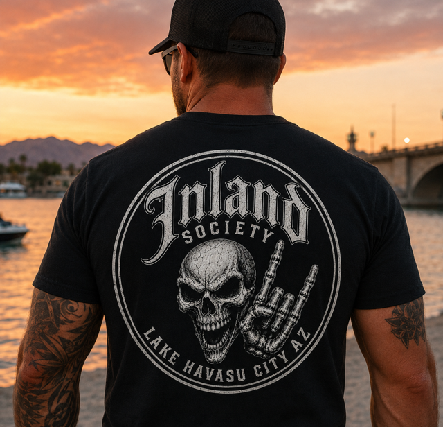 Man wearing black Inland Society skull and rock hand tee at sunset