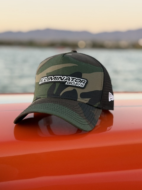 Camo Eliminator Boats trucker hat with white rubber patch on an orange boat deck